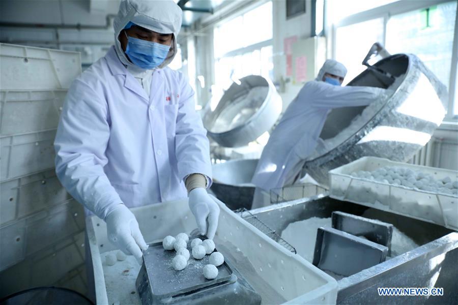 Cooks make Yuanxiao, glutinous rice flour dumpling with sweetened stuffing, at a workshop of Daoxiangcun, a time-honored foodstuff company, in Beijing, capital of China, Feb. 18, 2016.