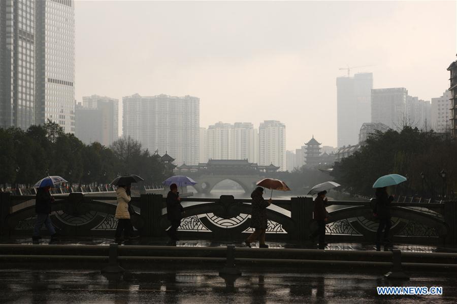 People walk on a bridge above Jinjiang River in light rain in Chengdu, capital of southwest China's Sichuan Province, Feb. 23, 2016. Chengdu received a light rain on Tuesday. 