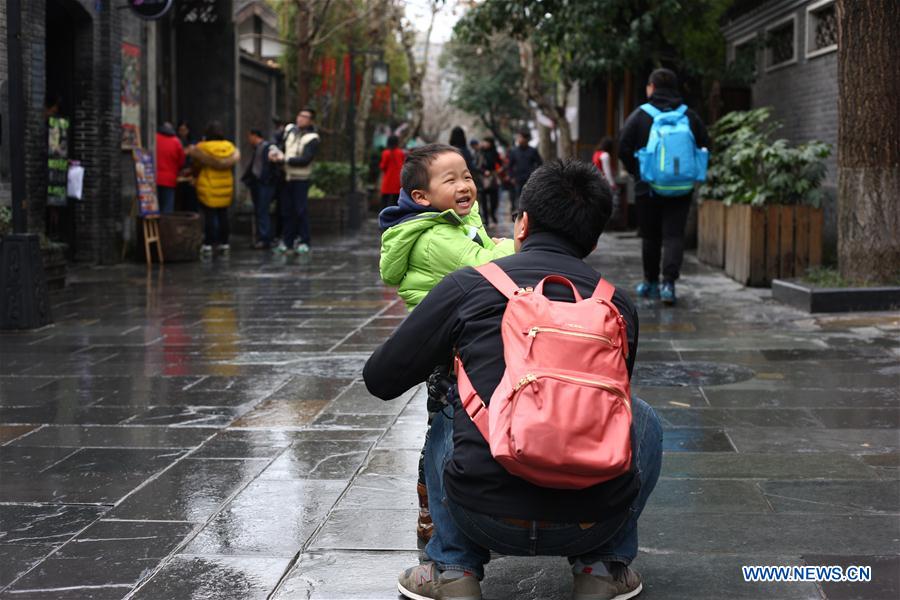 People go sightseeing in light rain at the Wide and Narrow Alleys in Chengdu, capital of southwest China's Sichuan Province, Feb. 23, 2016. Chengdu received a light rain on Tuesday. 