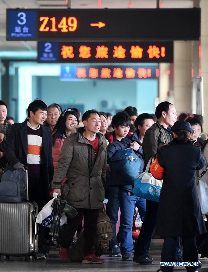 Passengers carrying their luggage walk to a platform at the railway station of Zhengzhou, capital of central China's Henan Province, Feb. 24, 2016. 