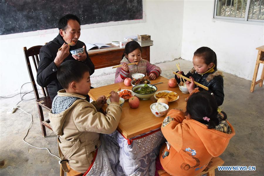 Primary school teacher Tao Chaolei, 52, has lunch with his four students, including one in grade three and three pre-school kids, at the start of the new term at Sujiacun Village of Wushan County in southwest China's Chongqing, Feb. 24, 2016. 