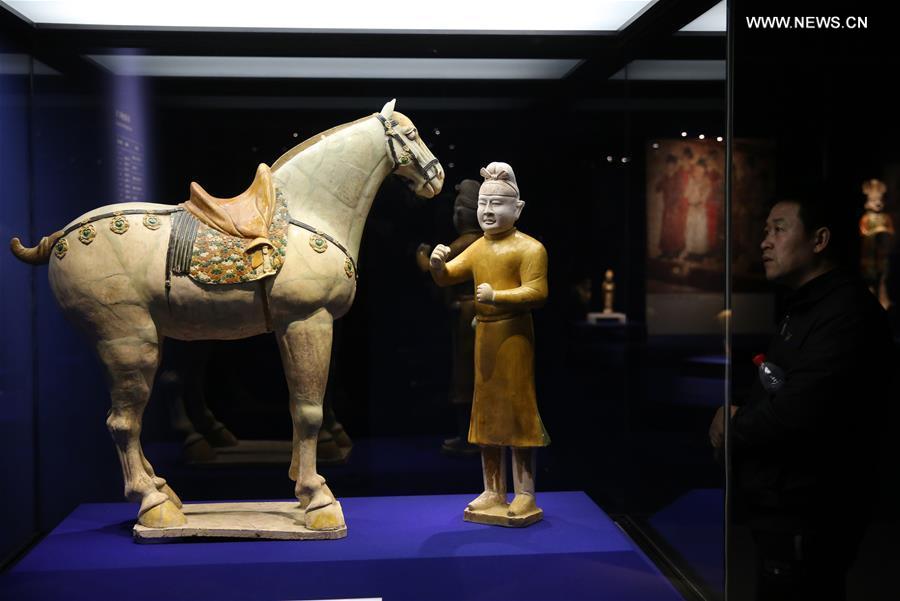 A visitor looks at a tri-colored glazed pottery work is seen displayed at an exhibition in Shaanxi History Museum in Xi'an, capital of northwest China's Shaanxi Province, March 23, 2016. 