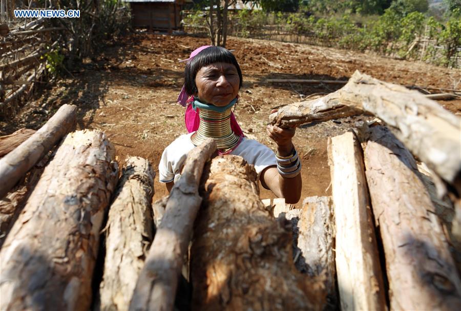 A Padaung woman with brass rings around her neck arranges dried woods at her house in Panpet Village, Demoso Township, Kayah State, Myanmar, April 11, 2016.