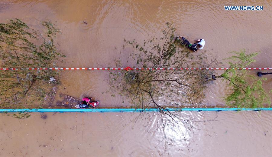 Riders struggle with their bikes in flood in Liuzhou, south China's Guangxi Zhuang Autonomous Region, April 11, 2016. 