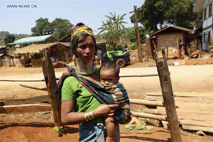 A Padaung woman with brass rings around her neck carries her child in Panpet Village, Demoso Township, Kayah State, Myanmar, April 11, 2016. 