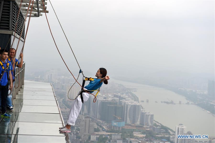 A tourist fastened by safty belt experiences hanging in the air on the Yunding glass-made plank road on a skyscraper in Liuzhou, south China's Guangxi Zhuang Autonomous Region, May 5, 2016.