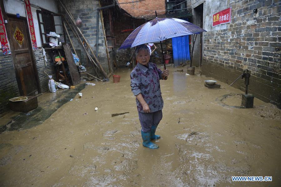 An old lady stands in front of her flooded home in Lichuan County, east China's Jiangxi Province, May 9, 2016.