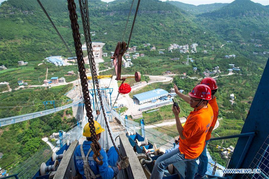 Workers install the last main cable backstay at the construction site of Fuma Yangtze River Bridge in Wanzhou of Chongqing, southwest China, May 30, 2016.