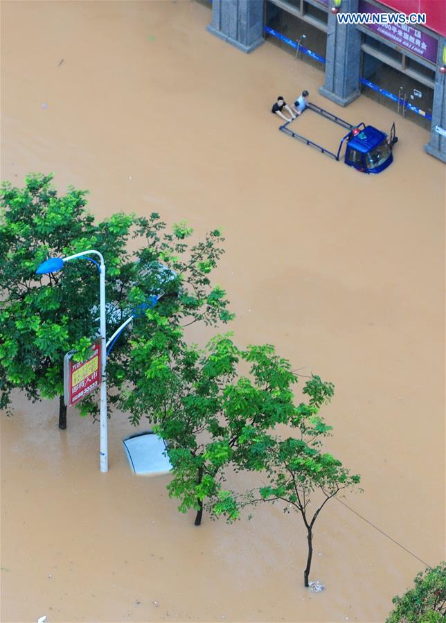 People push a stranded vehicle on a flooded road in Jiujiang City, east China's Jiangxi Province, July 2, 2016.