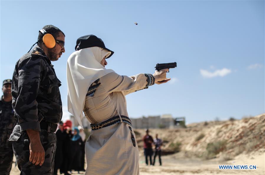 A Palestinian girl aims a pistol as she prepares to fire at a target during a training session for the families of Hamas officials, organized by Hamas-run Security and Protection Service, in Khan Younis in the southern Gaza Strip, July 24, 2016.