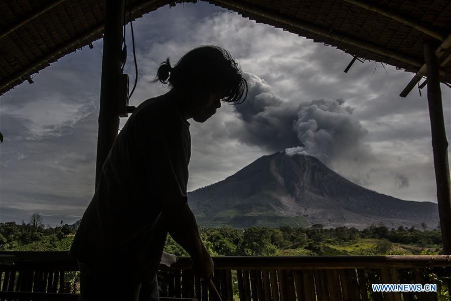 A woman watches the eruption of Mount Sinabung at Tiga Pancur village in Karo district, North Sumatra, Indonesia, July 24, 2016.