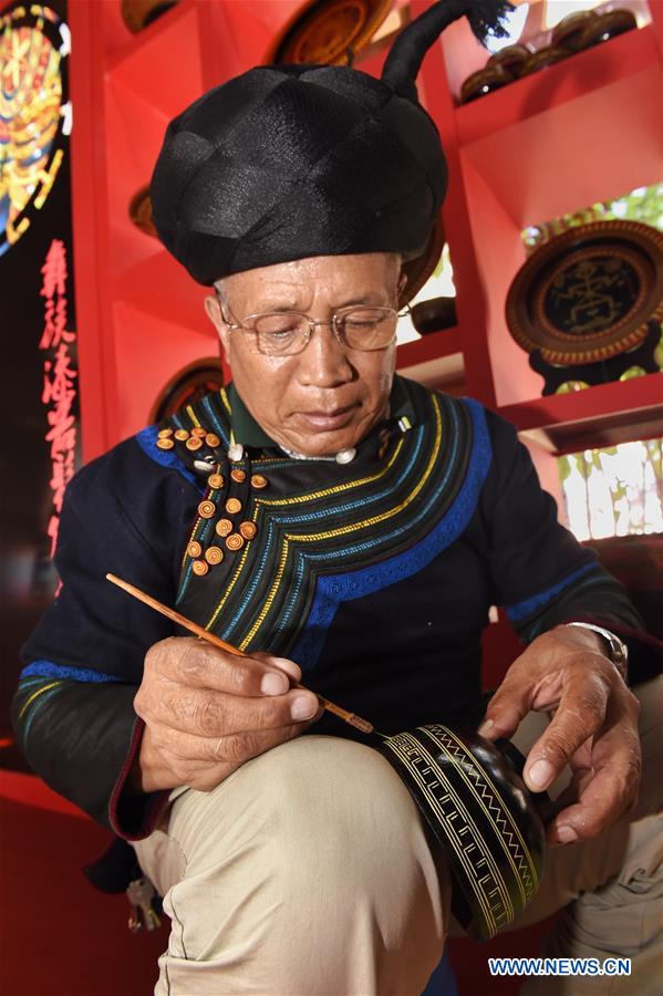 A folk artist paints on a lacquer during an intangible cultural heritage show of Liangshan Yi Autonomous Prefecture, in Xichang, southwest China's Sichuan Province, July 26, 2016. 