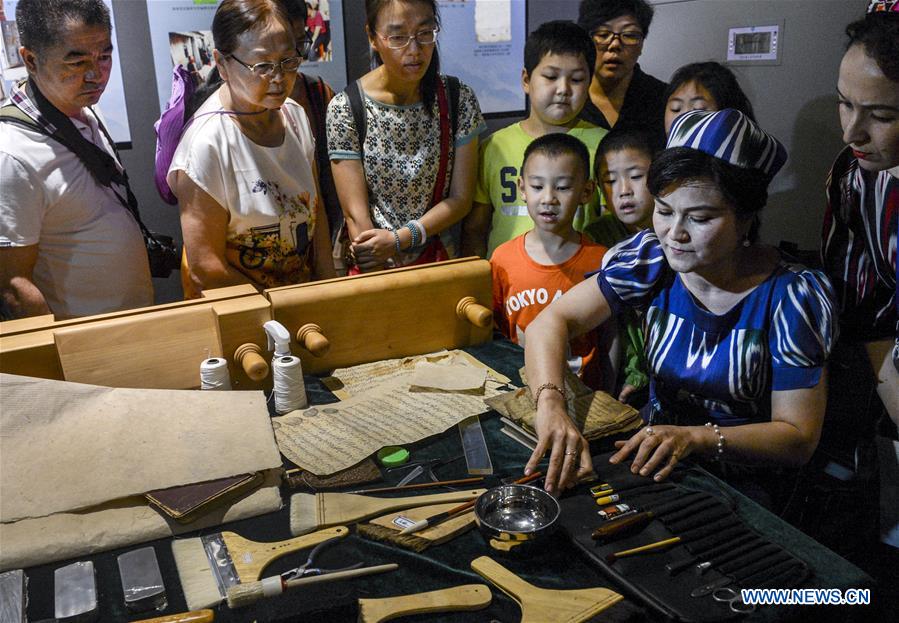 Visitors look at ancient books and documents of ethnic minorities in China displayed at Xinjiang Uygur Autonomous Region Musuem in Urumqi, capital of Xinjiang in northwest China, July 26, 2016. 