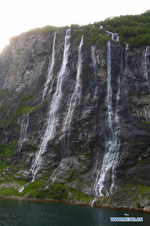 Tourists take a boat to appreciate a waterfall at Geirangerfjord in Norway, July 20, 2016.