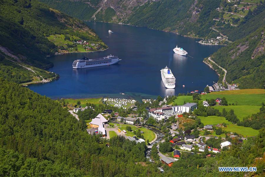 Tourists take a boat to appreciate a waterfall at Geirangerfjord in Norway, July 20, 2016.