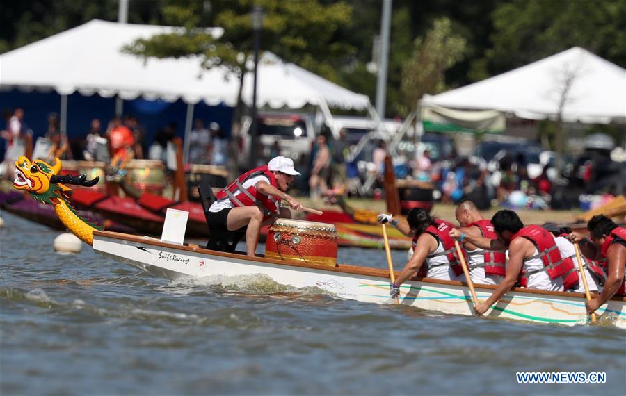 Dragon boat players cheer for the completion of a competition during the Hong Kong Dragon Boat Festival in New York (HKDBF-NY) held in Corona Park of New York, the United States, Aug. 7, 2016.