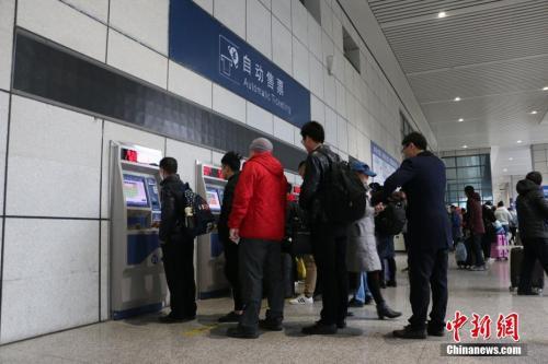 Passengers queue to buy train tickets through vending machines. [File photo: Chinanews.com]