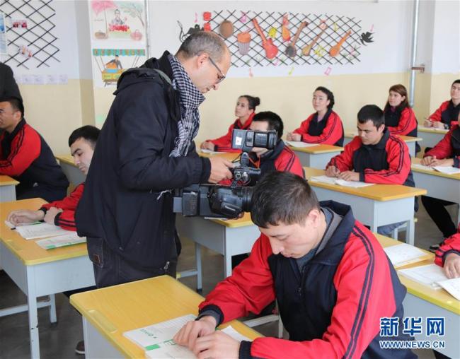 Hamdi Emam, a cameraman for Nile TV, is shooting students studying at Kashgar Vocational Training Center. [Photo: Xinhua]