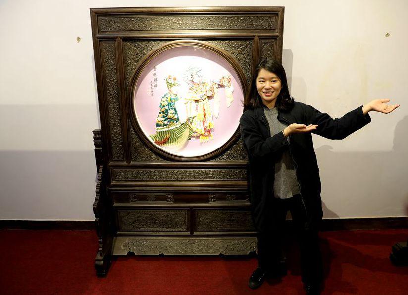 Kim Dongdae, director of the World Heritage Team, poses with a cloth paste painting on March 27, 2019, in Fengning Manchu autonomous county, Hebei province.(Photo by Fu Rui/chinadaily.com.cn)