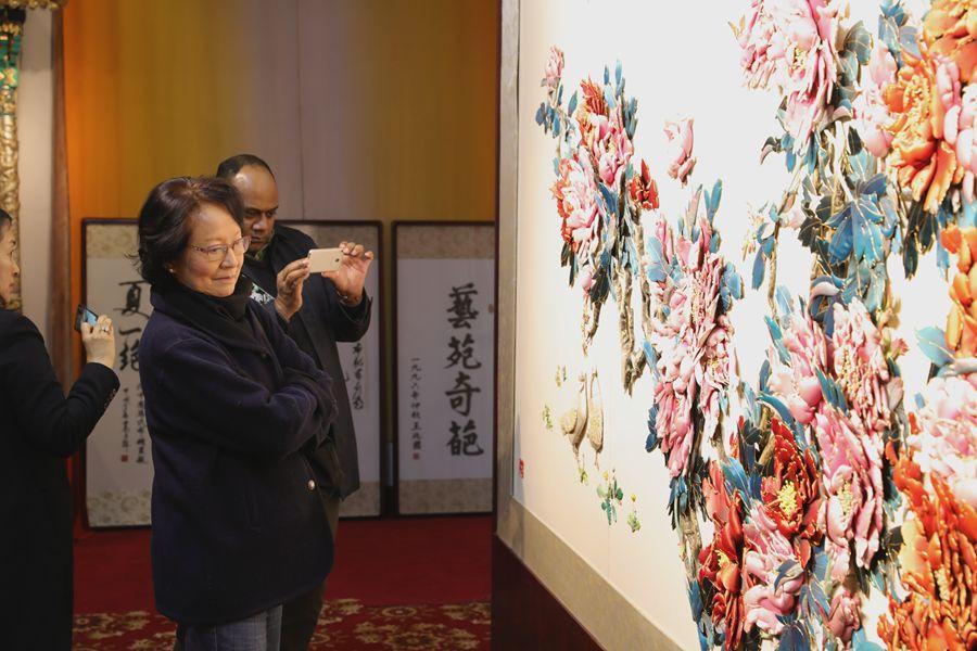 Experts from UNESCO are drawn to one of the most famous local works of intangible cultural heritage, a cloth paste painting, on March 27, 2019, in Fengning Manchu autonomous county, Hebei province.(Photo by Fu Rui/chinadaily.com.cn)