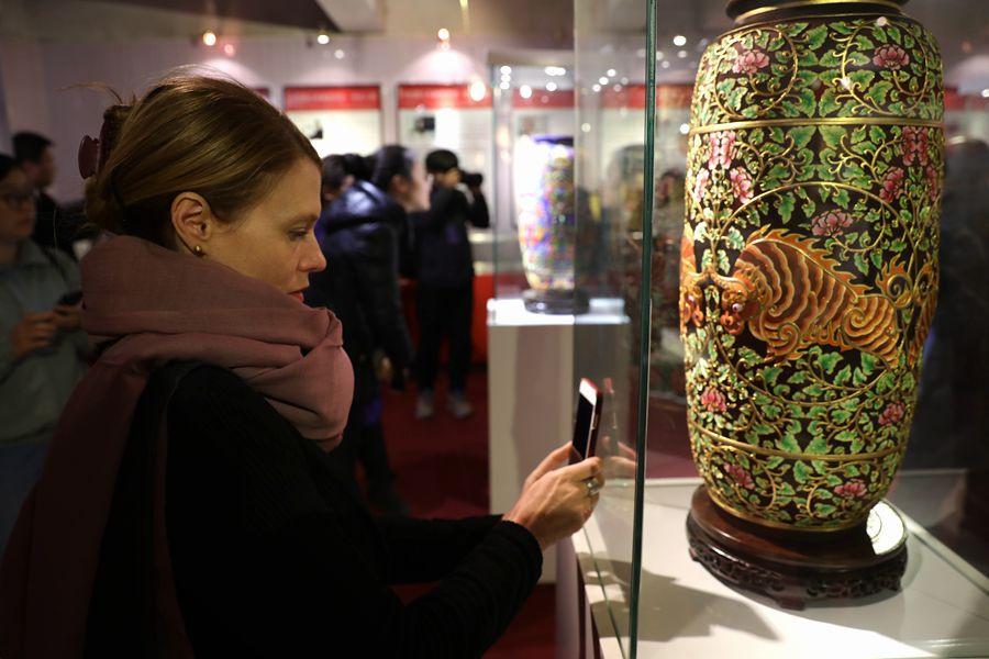 Suzzanne Ogge, UNESCO facilitator for intangible cultural heritage, takes a photo of delicate cloth paste painted patterns on a vase on March 27, 2019, in Fengning Manchu autonomous county, Hebei province.(Photo by Fu Rui/chinadaily.com.cn)