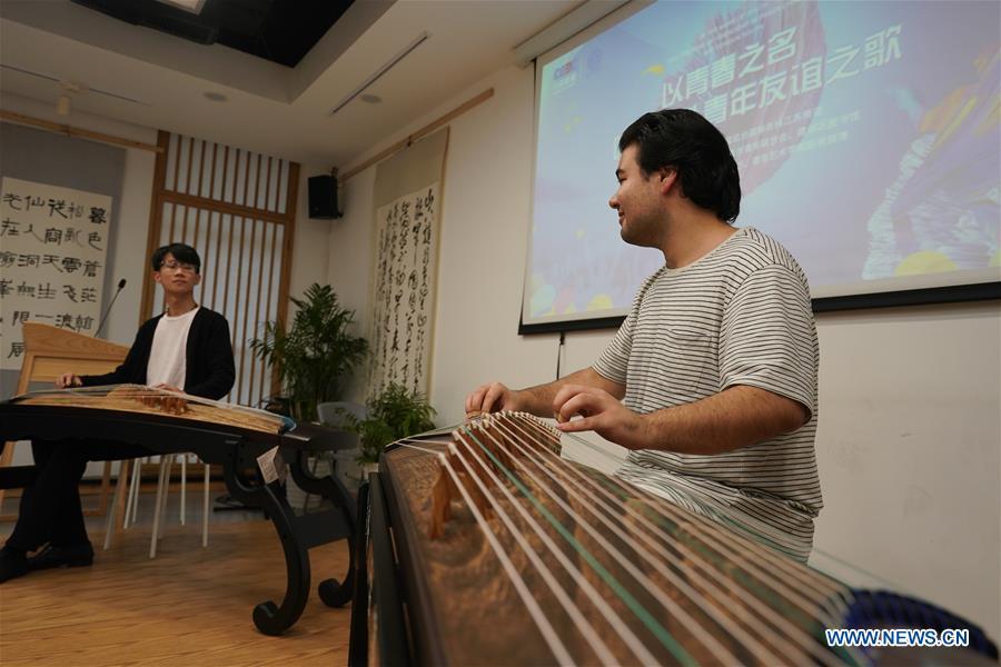 Garzan Yashar (R) from the United States and professional Chinese zither artist Huang Yuzhe play Chinese zither in Nanjing, capital of east China\'s Jiangsu Province, April 28, 2019. A cultural exchange event between young representatives from Nanjing and foreign students from Nanjing University of the Arts was held in Nanjing. (Xinhua/Ji Chunpeng)