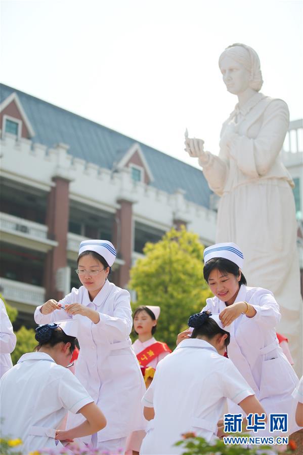 学生们身穿护士服,在南丁格尔像前参加仪式,迎接即将到来的